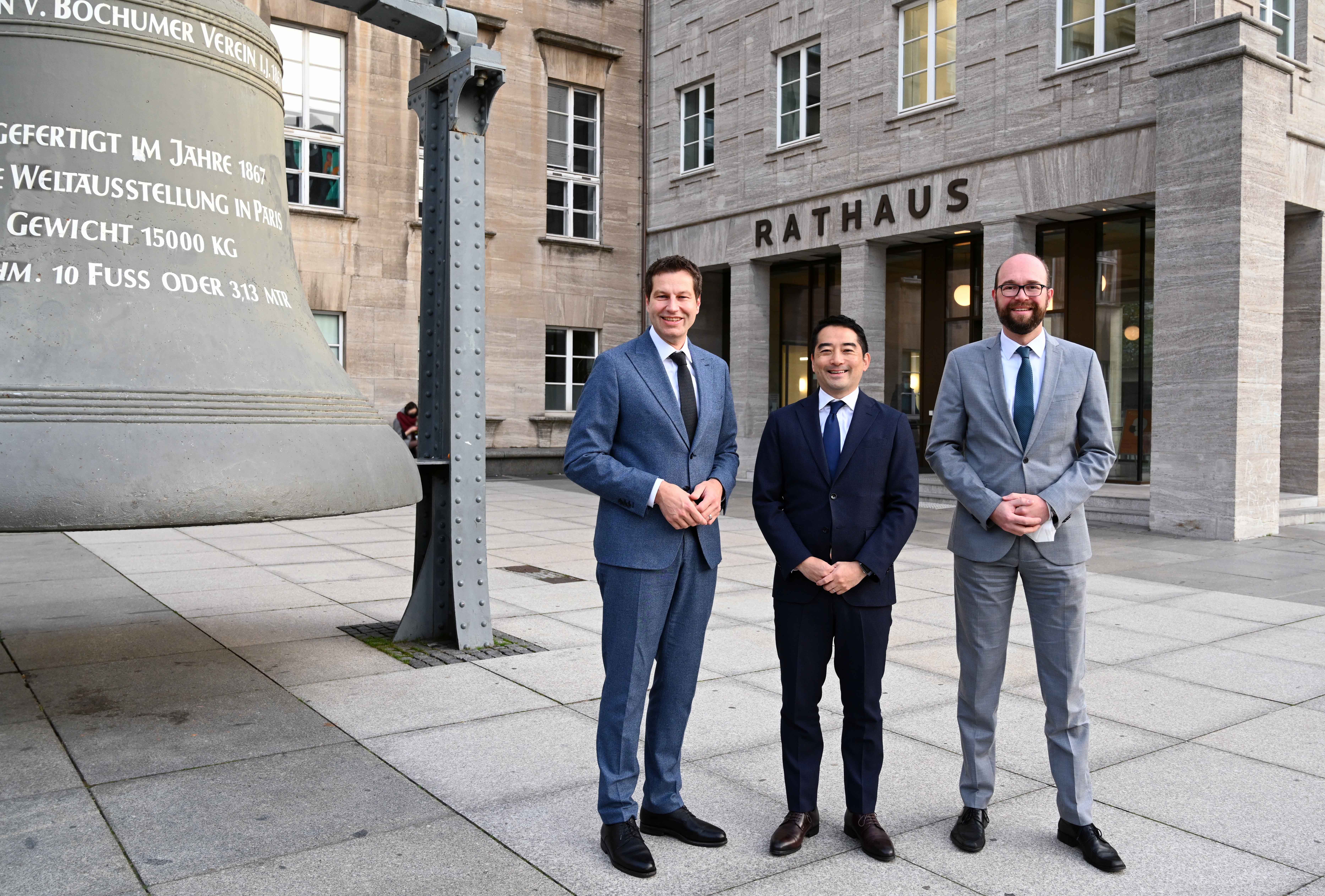 Besuch einer Delegation aus Tsukuba: Thomas Eiskirch (Oberbürgermeister Stadt Bochum), Dr. Tatsuo Igarashi (Oberbürgermeister von Tsukuba), Sebastian Kopietz (Stadtdirektor Stadt Bochum) - zwischen Glocke und neuem Osteingang des Rathauses Bochum