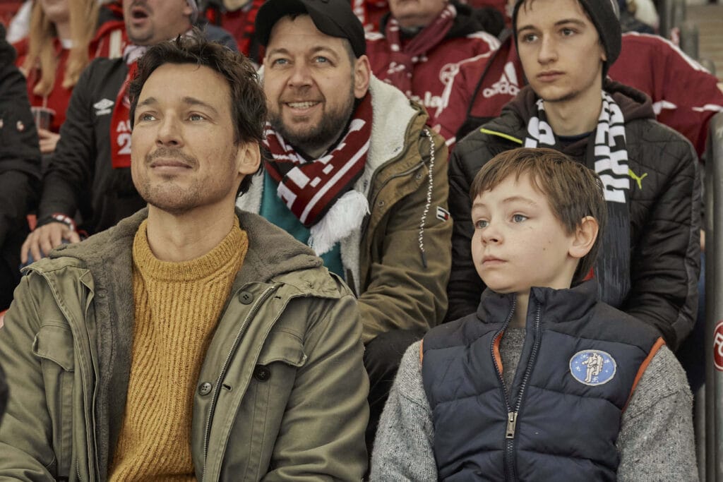 Das erste Mal gemeinsam im Stadion: Mirco (Florian David Fitz) und Jason (Cecilio Andresen), im Hintergrund: Mirco und Jason von Juterczenka