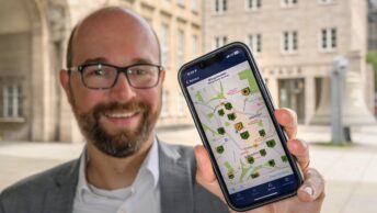 Sebastian Kopietz (mit der neuen Mängelmelder-App auf einem Handy)