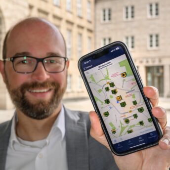 Sebastian Kopietz (mit der neuen Mängelmelder-App auf einem Handy)